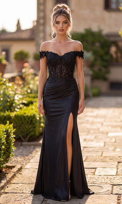 Outdoors in daylight, a woman stands on a stone path surrounded by greenery and a building, wearing the Long Prom Dress: Chicas J054 in black—an off-the-shoulder gown featuring a stunning lace bodice, luxurious stretch satin fabric, and a thigh-high slit.