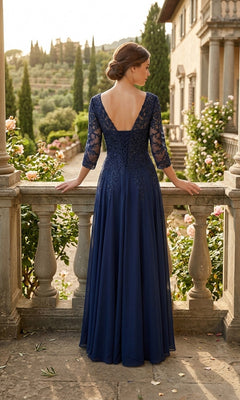 A woman in the Long Prom Dress: Chicas J070—a navy blue chiffon evening gown with lace sleeves—stands on a stone balcony, facing away as she overlooks a garden filled with trees and flowers.