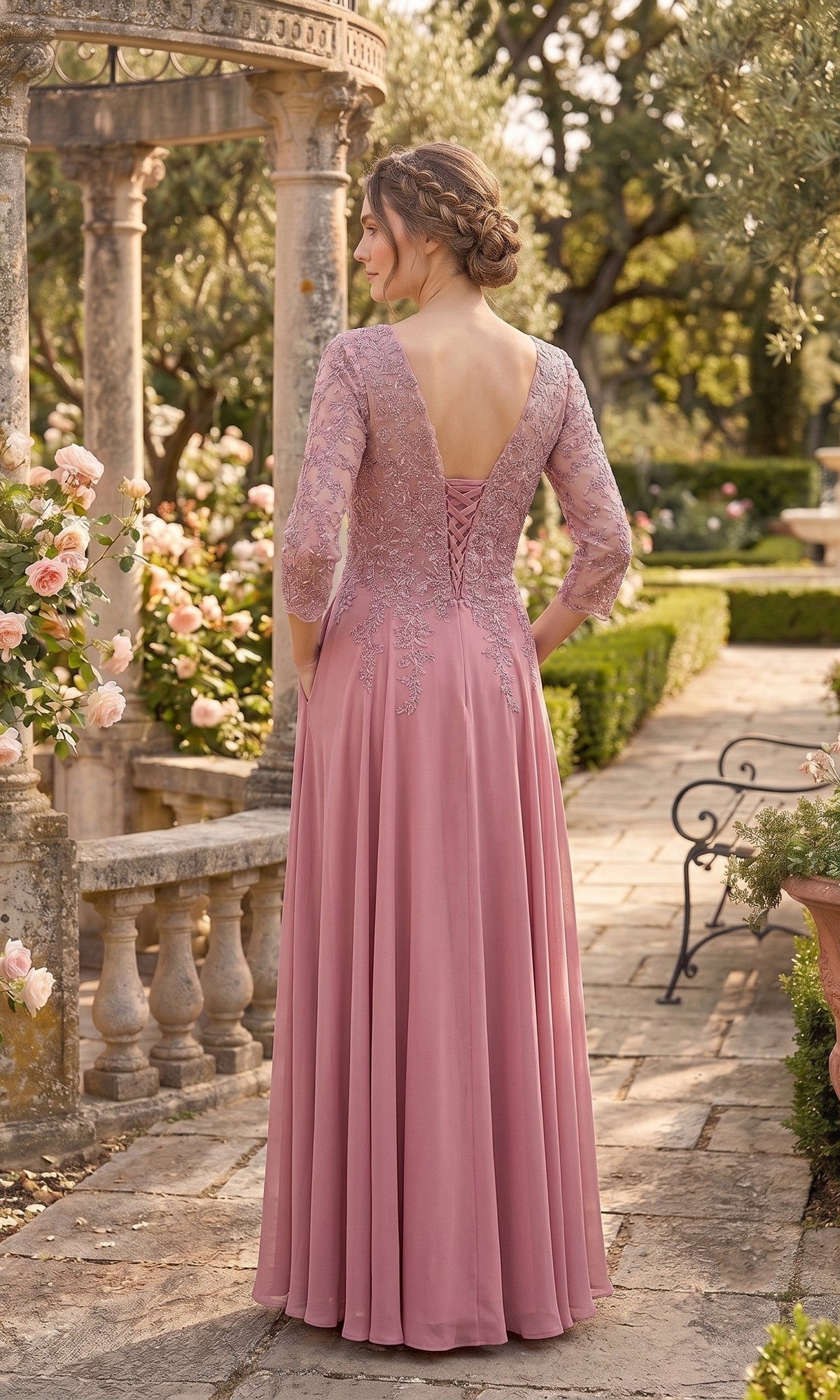Wearing the Chicas J070 Long Prom Dress, a woman in a mauve lace gown with three-quarter sleeves stands on a stone garden path among roses and greenery, her back to the camera.