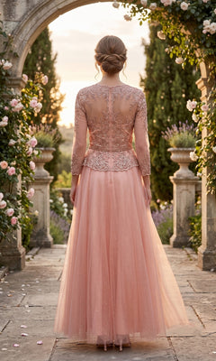 A woman stands outdoors on a stone path, surrounded by flowers and greenery, wearing the Long Prom Dress: Chicas J082—a pink, floor-length gown with intricate embroidery and an embellished bodice.