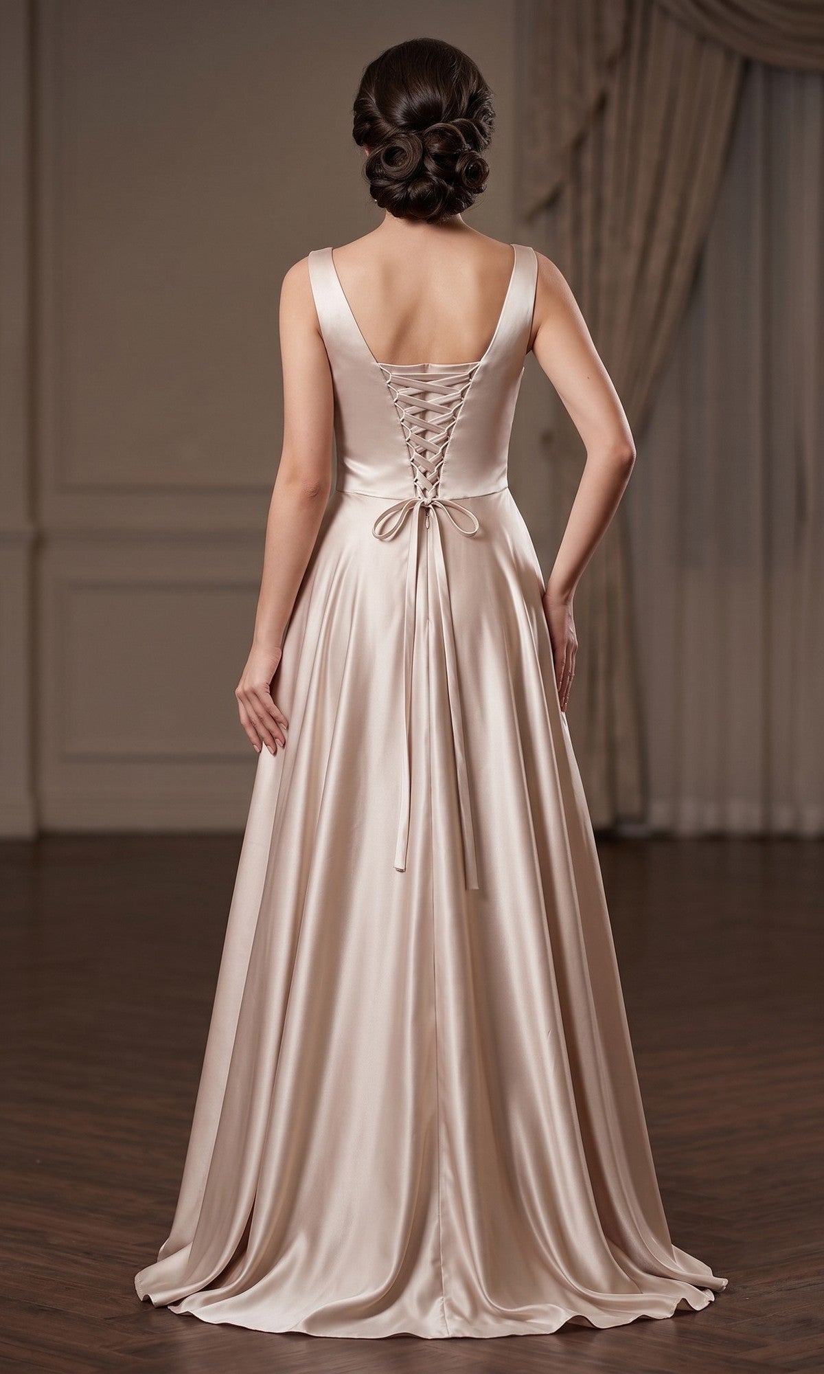 A woman wearing the Long Prom Dress: Chicas J112, an elegant floor-length satin gown with a lace-up back, stands on a wooden floor in a formal, neutral-toned room.