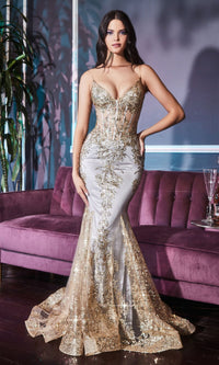 Woman modeling a long gold mermaid dress with sparkly embellishments, standing inside in front of a purple velvet couch.