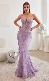 A woman in a lavender purple long mermaid prom dress standing in a white room with disco ball props in the background.