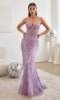 A woman in a lavender purple long mermaid prom dress standing in a white room with disco ball props in the background.