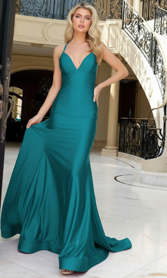 A woman in a teal Strappy-Back Long Prom Dress (Jessica Angel 2415) stands indoors by ornate wrought iron railings and marble floors, holding part of her gown.