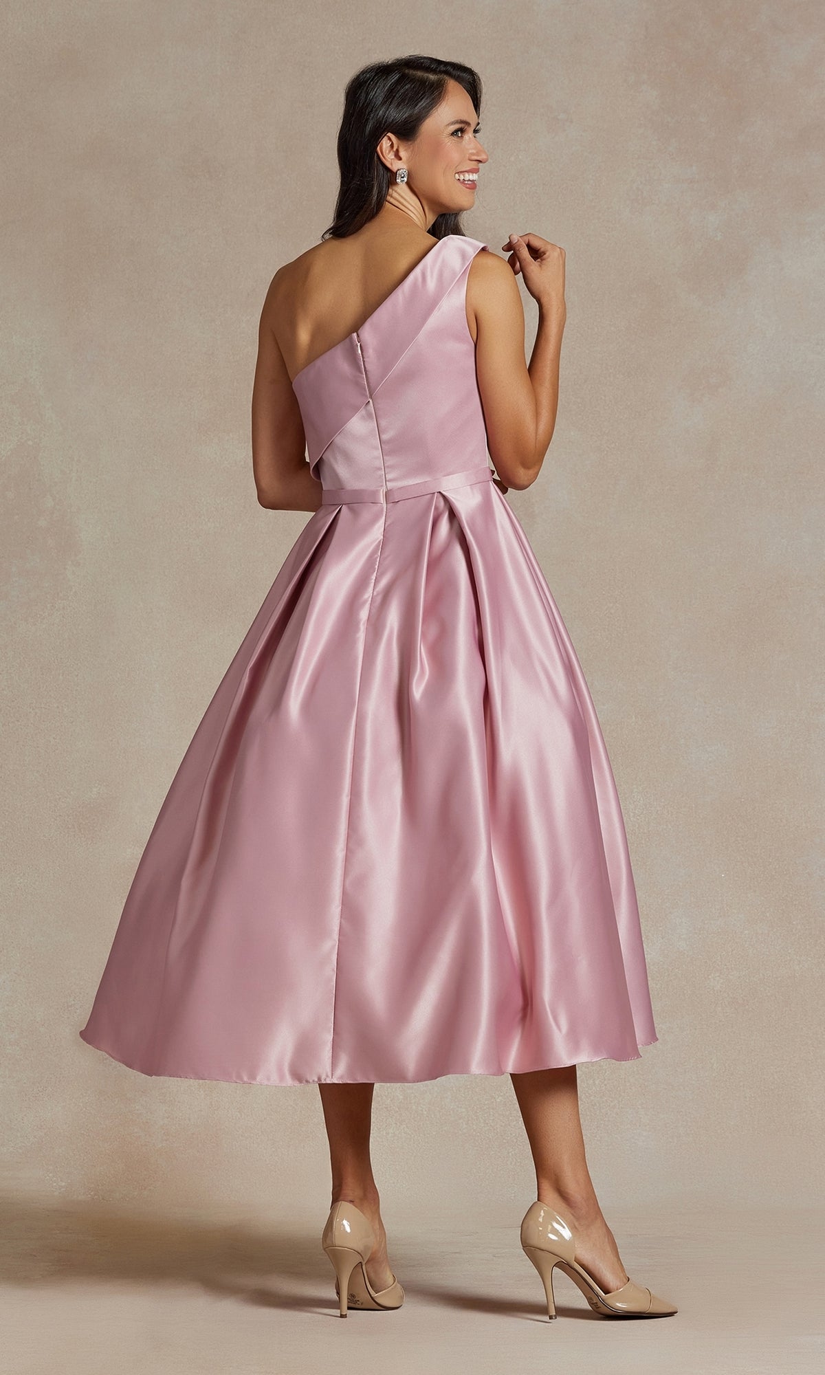 A woman models the One-Shoulder Simple Tea-Length Party Dress JE931 in shiny light pink, featuring a flared skirt, styled with nude heels and set against a neutral background.