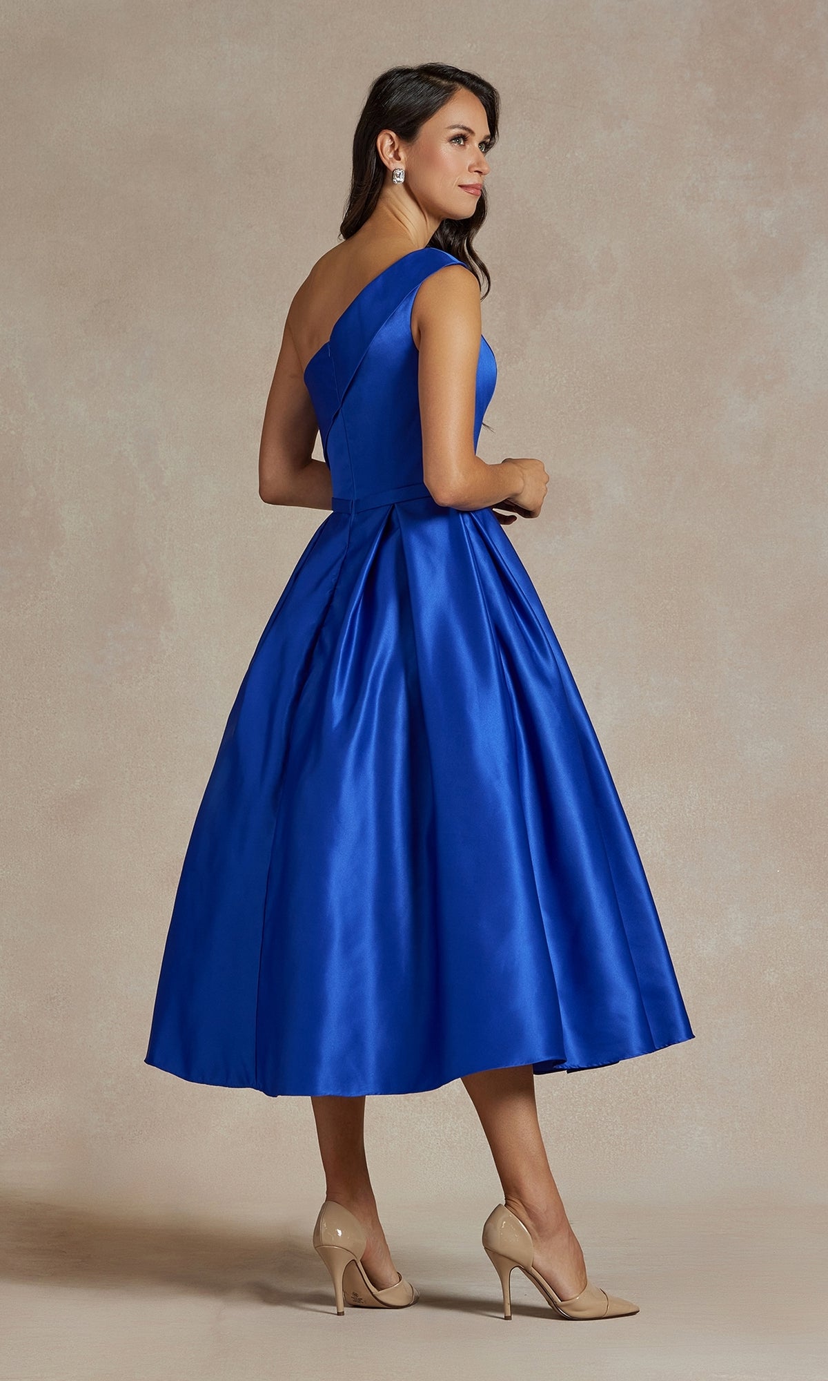A woman wears the One-Shoulder Simple Tea-Length Party Dress JE931 in royal blue, paired with beige high heels, standing on a neutral background.