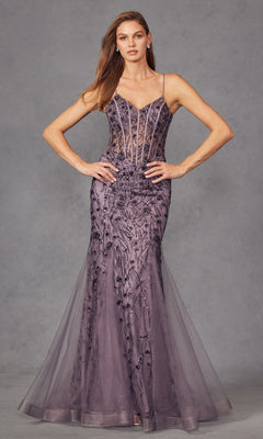 A woman stands with hands on hips wearing the Long Sequin Mermaid Prom Dress: Juliet JT2441S, a floor-length gown with sheer bodice, thin straps, and intricate sequin details against a gray studio background.