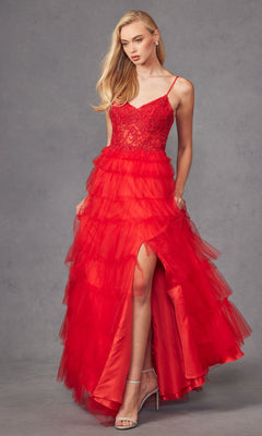 A woman models the Juliet JT2451S Long Ruffled Prom Ball Gown in red tulle with spaghetti straps, a lace bodice, and high slit, posing against a plain grey background.