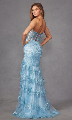 A woman poses gracefully against a neutral gray background wearing the Long Prom Dress JT2455K by Juliet, a strapless mermaid gown in pastel powder blue with lace detailing and tiered ruffles.