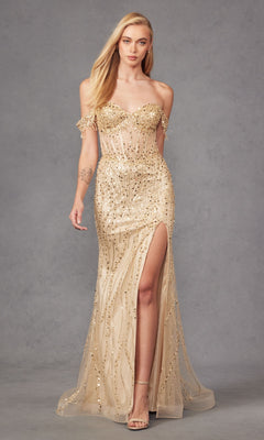 A woman stands against a plain gray background wearing the Juliet JT2471L Fringed Long Sequin Prom Dress, a strapless nude-colored formal gown with gold embellishments and a thigh-high slit.