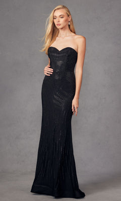A woman poses against a gray backdrop in the Juliet JT2472R, a strapless long black sequin prom dress with subtle shimmering lines, perfectly complementing her long blonde hair.