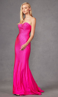 A woman models the Juliet JT2472R Strapless Long Sequin Prom Dress, a form-fitting, floor-length hot pink gown with vertical stripe details, posing against a plain gray background.