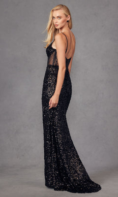 A woman poses in the Long Prom Dress JT2474U by Juliet—a sleeveless, floor-length black sequin gown with a corset bodice and sheer side panel—glancing over her shoulder against a plain gray background.