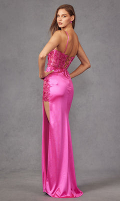 A woman models the Long Prom Dress JT2476U by Juliet—a fitted, bright pink satin gown with lace embroidery, thin straps, and a high slit—against a plain gray background.