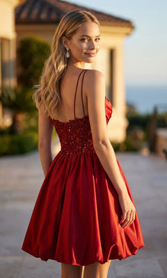 A woman with long blond hair wears the Juliet JT7186A short homecoming dress—a sleeveless, red satin A-line style—as she stands outdoors, looking back over her shoulder.