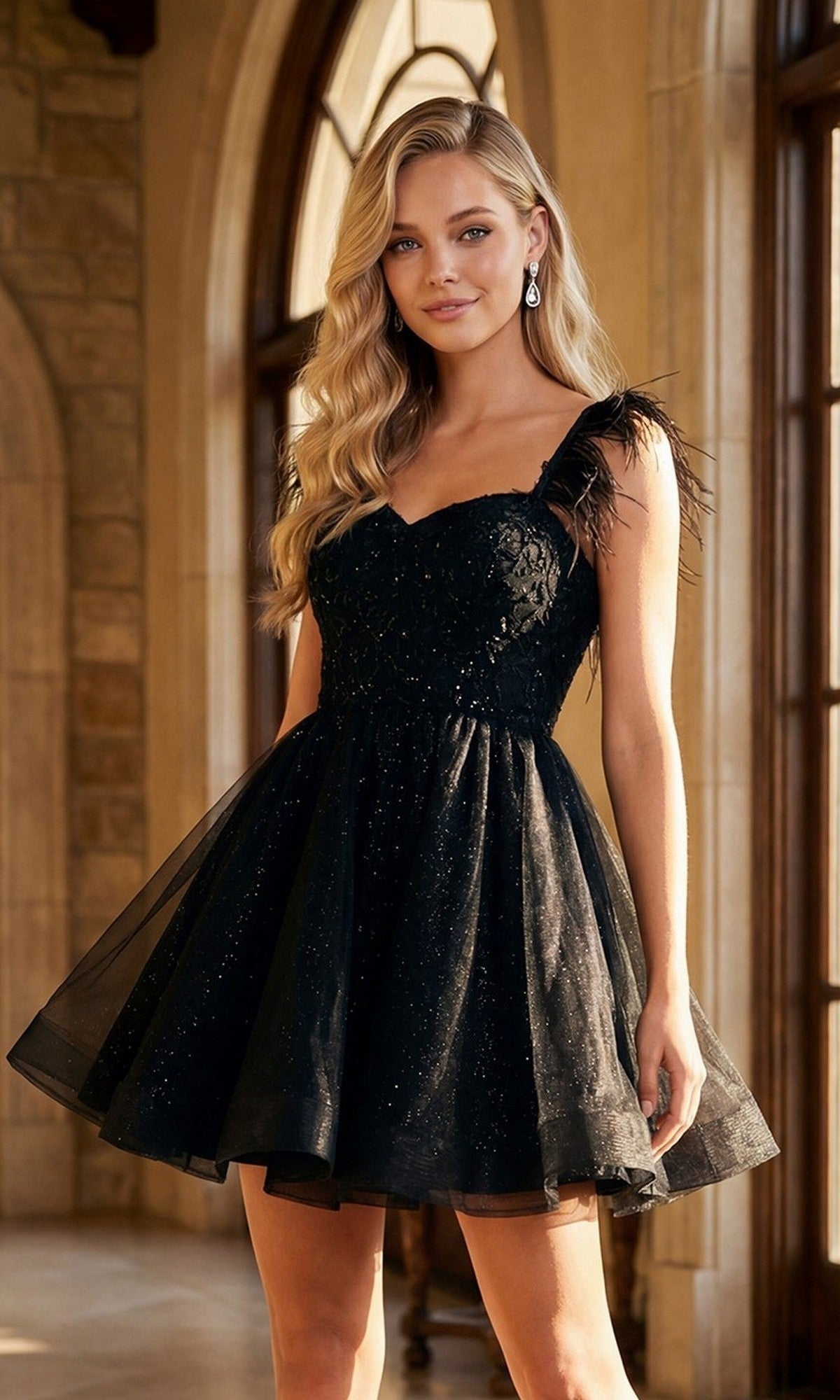 A woman wearing the Juliet JT881 short black homecoming dress, featuring lace and feathered straps, stands indoors near large arched windows.