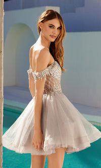 A woman in a Short Champagne Corset Prom Dress, Juliet JT947L in silver, stands by the pool and looks over her shoulder with a neutral expression.