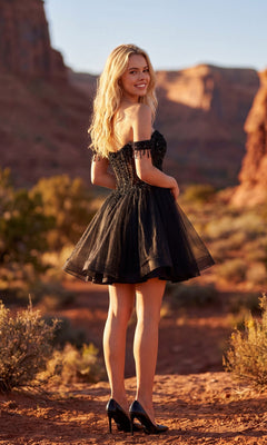 A woman in the Short Champagne Corset Prom Dress: Juliet JT947L and black heels stands on a rocky path amid desert scenery with dramatic red rock formations in the background.