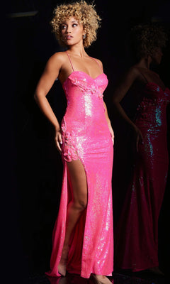 A person stands against a dark background wearing the Jovani JVN38592 long prom dress, featuring bright pink sequins, a high slit, spaghetti straps, floral accents, and a lace-up back.