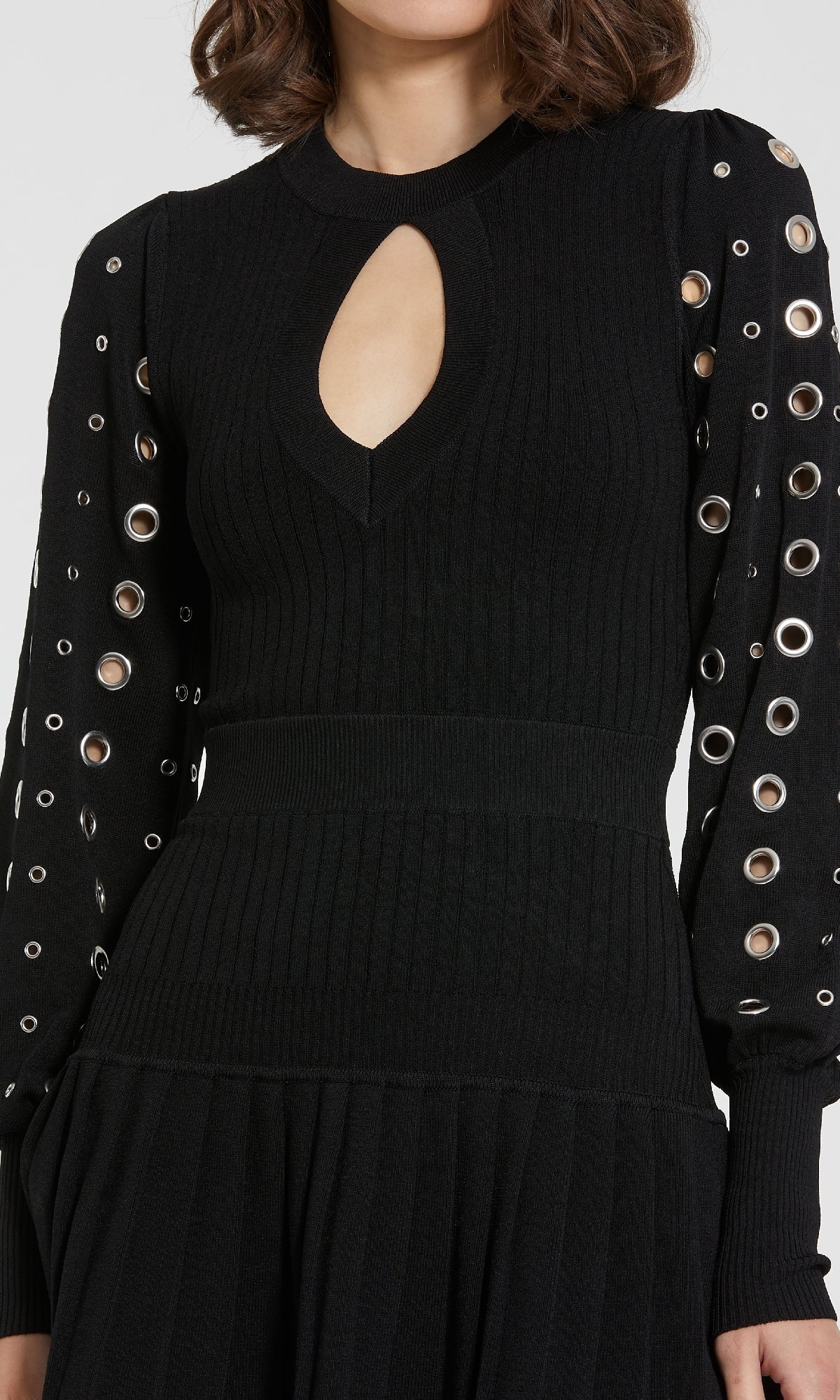 A woman wears the Mac Duggal K1007 long sleeve black party dress featuring a keyhole neckline and silver grommet details.