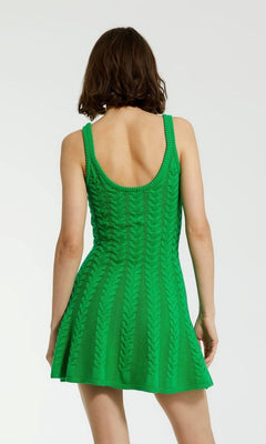 A person with short brown hair is shown from the back, wearing the Mac Duggal Designer Short Knit Dress K12004, a sleeveless green chunky knit dress with a scoop back, against a plain background.