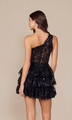 A woman models the One-Shoulder Short Sequin Homecoming Dress K855, featuring a black, tiered ruffle skirt and corset waist, standing against a plain beige background with her back to the camera.