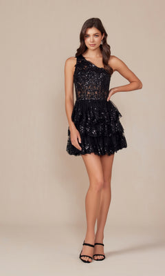 A woman stands in the One-Shoulder Short Sequin Homecoming Dress K855, a black, tiered A-line party dress with sequins and black heels, against a plain beige background.