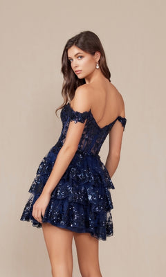 Woman wearing the Off-Shoulder Short Ruffled Sequin Hoco Dress K856 in navy blue, with a fitted bodice and tiered skirt, stands against a plain beige background.