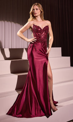 A woman stands on pale steps wearing the Ladivine KV1112, a strapless long burgundy prom dress with a fitted silhouette, thigh-high slit, and floral embellishments on the bodice.