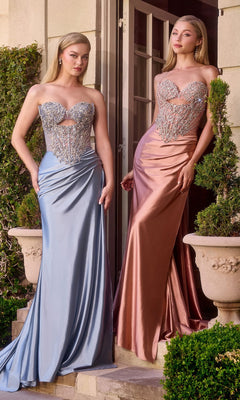 Two women pose gracefully outdoors before a building and lush potted plants, wearing Ladivine KV1135 long prom dresses featuring beaded corset bodices and satin skirts—one in dusty blue and one in rose gold.