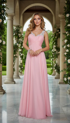 A woman in the Sheer-Back Long A-Line Prom Dress: La Femme 21130, with jeweled straps, stands in a marble colonnade garden filled with greenery and white flowers—her elegant gown perfect for any special occasion.