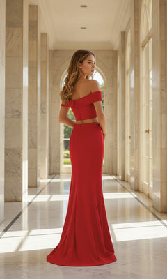 A woman wearing the La Femme Two-Piece Off-Shoulder Prom Dress 25578 stands in a marble hallway with tall windows, facing away from the camera.