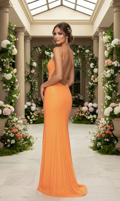 A woman in a dazzling Backless High-Neck La Femme Long Sequin Prom Dress stands in a flower-adorned hallway with columns and a glass ceiling, elegantly looking over her shoulder.