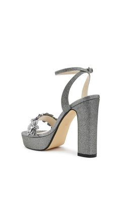 Lily Pewter Platform Prom Shoes: Touch Ups 4710 are silver glitter platform high heel sandals with an ankle strap, a rhinestone flower embellishment on the toe, and a pewter finish.