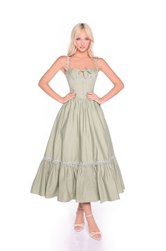 A woman faces forward wearing the Lioren Sage Green Casual Midi Dress, featuring a corset bodice, ruffled skirt, lace-up back, and paired with light sandals.