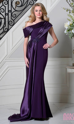 A woman poses gracefully indoors by a staircase in the Marsoni M346 Asymmetrical Long Formal Dress, an off-the-shoulder, floor-length gown in elegant eggplant with draped satin and floral embellishments.