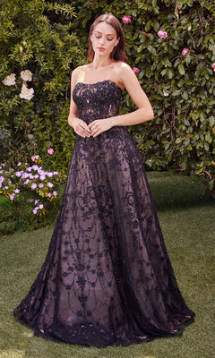 A woman stands outdoors on grass, wearing the Andrea & Leo MA104 Long Sleeve Long Formal Dress with a sheer lace overlay, surrounded by green foliage and blooming flowers.