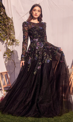 A woman stands outside in the Andrea & Leo MA107 long-sleeve black formal dress, holding the skirt out as sequin embellishments catch the light.