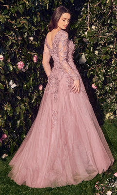 A woman stands outdoors before greenery, wearing the Andrea & Leo MA108: a mauve long sleeve formal gown with tulle fabric and intricate lace floral appliques.
