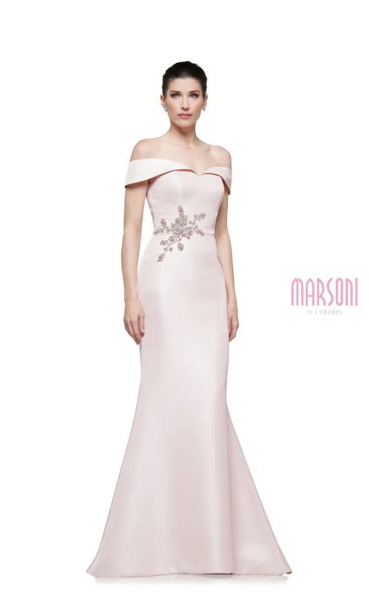 A woman wears the Marsoni MV1003 long formal dress—pale pink, off-the-shoulder satin with beaded floral detail at the waist—standing against a plain white background. 