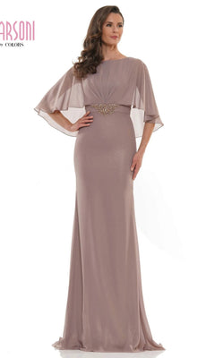A woman stands in front of a white background wearing the Marsoni MV1130 Long Formal Dress, a modest floor-length taupe sheath with sheer cape sleeves and a decorative waistband.