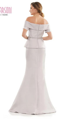 A woman faces away from the camera, wearing the Marsoni MV1144 long formal dress, which features an off-the-shoulder neckline, beaded peplum waistline, and decorative buttons down the back.