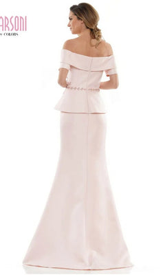 A woman is shown from the back wearing the Marsoni MV1144 long formal dress, featuring a light pink off-the-shoulder design, fitted bodice, beaded peplum detail, and flared skirt.