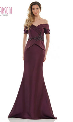 A woman poses against a white background in the Marsoni MV1144 long formal dress in wine, featuring an off-the-shoulder neckline, floor-length silhouette, and a beaded peplum accent at the waist.