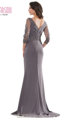 A woman models the Marsoni MV1145 long formal dress in mauve, featuring a fitted silhouette, sheer beaded sleeves, and a V-shaped back, while posing with her back to the camera.