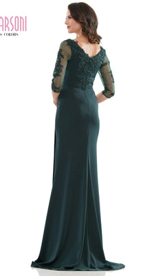 Woman wearing the Marsoni MV1146 long formal dress in dark green with lace sleeves and back detailing, standing and facing away from the camera.