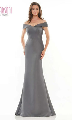 A woman models the Marsoni MV1153 long formal dress in charcoal, featuring a fitted off-the-shoulder design, against a plain white background.