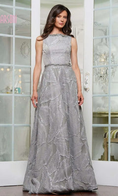 A woman poses indoors in front of glass-paneled doors, wearing the Marsoni MV1224 long formal dress in charcoal—a sleeveless gown with a subtle jacquard print and belted waist.
