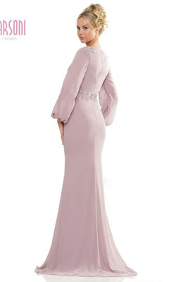 A woman wearing the Marsoni MV1273 long formal dress—fitted, floor-length, light mauve with a v-neckline, long sleeves, and lace waist detail—stands facing slightly away from the camera.